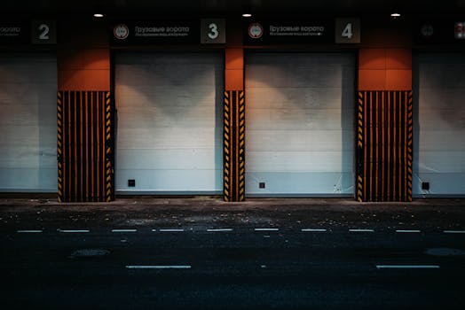 pexels-photo-2977309-2977309 Night view of a modern loading dock with closed garage doors in an urban area, showcasing industrial architecture.
